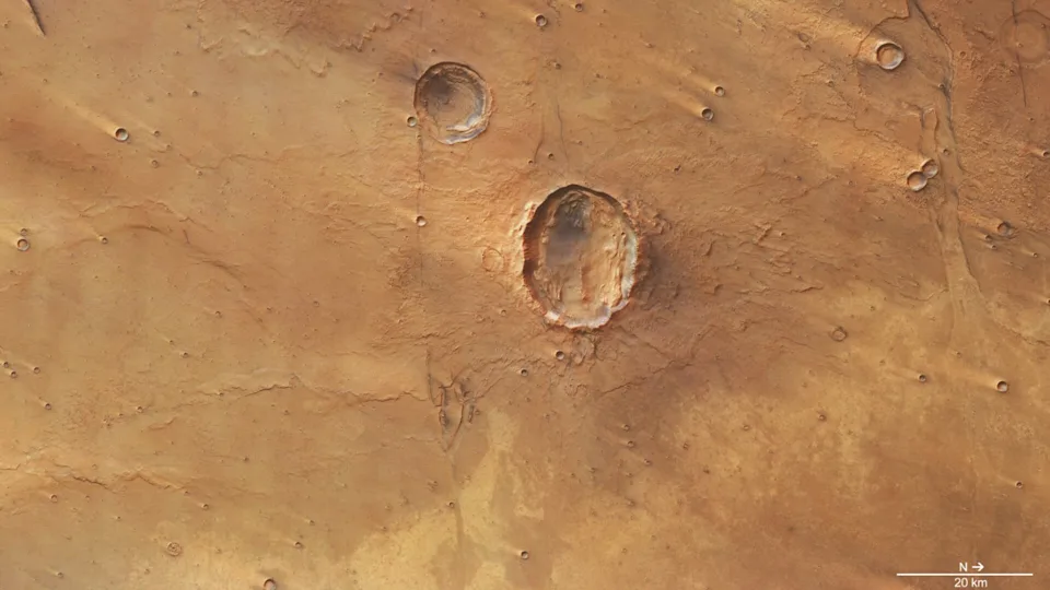 A photo of the surface of Mars from space, with a large crater seen in its reddish brownish surface